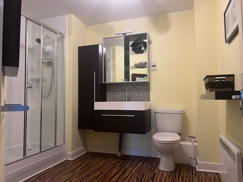 Modern bathroom with black vanity, white sink, toilet, shower enclosure and yellow walls