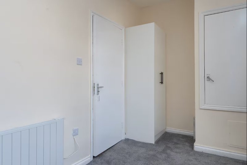 Empty hallway with white doors, radiator, and dark grey flooring