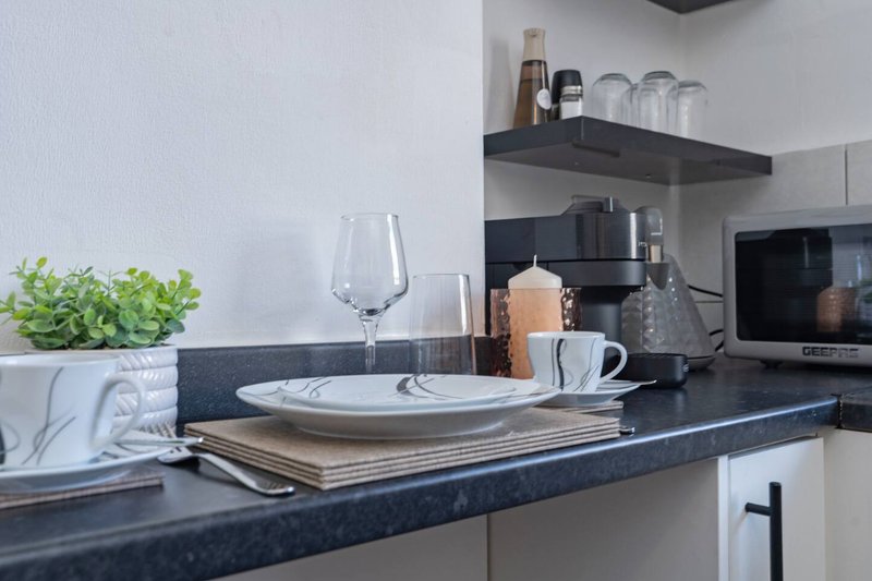 Modern kitchen with dark countertop, place setting, glassware and small potted plant