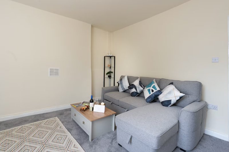 Living room with gray corner sofa, wooden coffee table, geometric rug and wall art