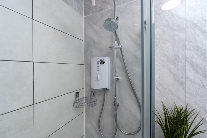 Modern bathroom with walk-in shower, grey tile walls, rainfall showerhead and potted plant