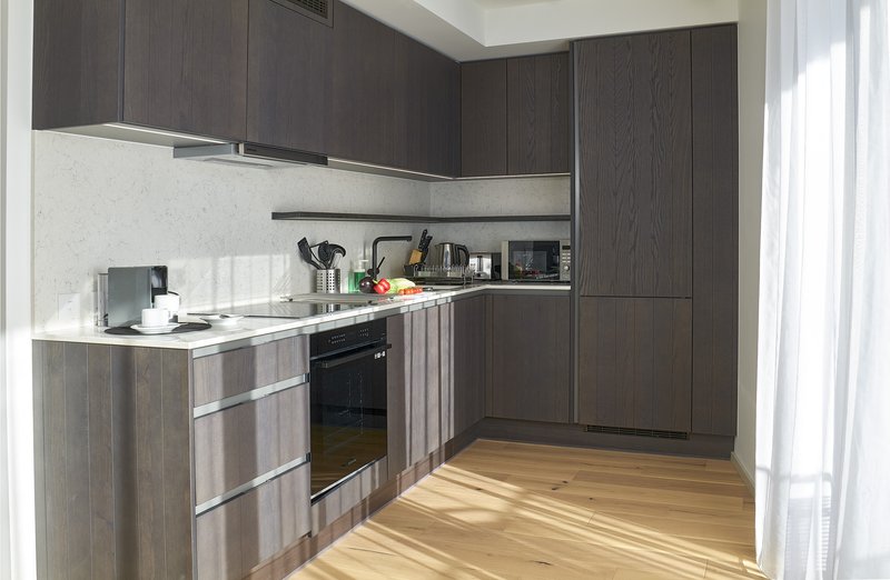 Modern kitchen with dark wood cabinets, white backsplash, stainless steel appliances and wooden flooring