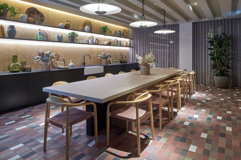 Modern dining room with white table, wooden chairs, black kitchen cabinetry and illuminated shelving