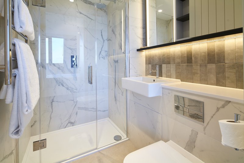 Modern bathroom with marble shower enclosure, white sink and toilet, heated towel rail