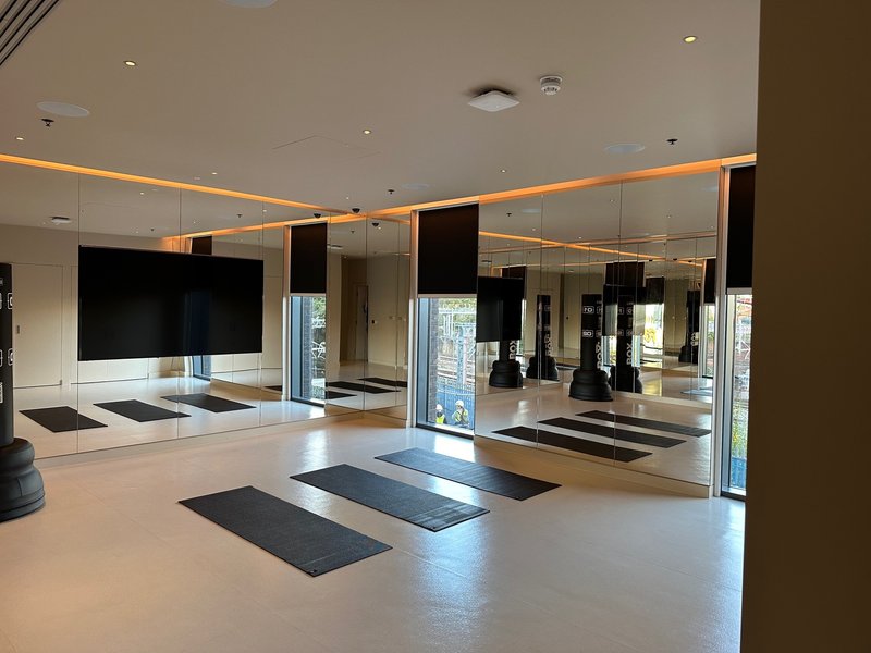 Modern gym studio with mirrored walls, yoga mats, TV screen and orange accent lighting