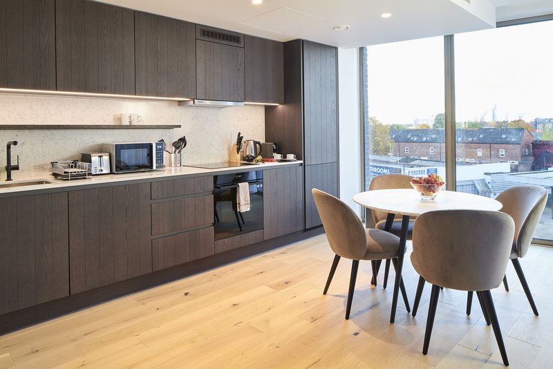 Modern kitchen and dining area with dark cabinets, wooden floor, and waterfront views through large windows