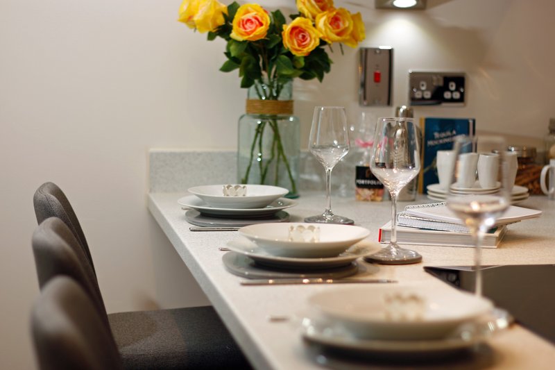 Dining table set with plates, glasses, and yellow roses in vase
