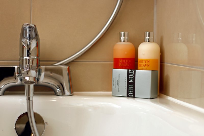 Bathroom sink with chrome faucet and toiletry bottles on counter