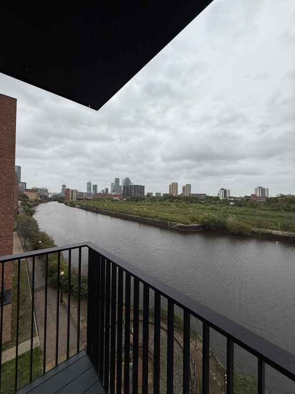 Balcony view of river with city skyline and cloudy sky in background