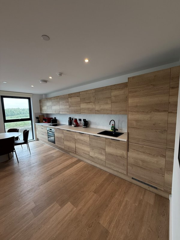 Modern kitchen with wooden cabinetry, white countertop, sink and integrated appliances