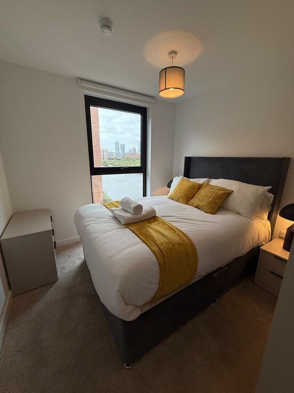 Modern bedroom with double bed, gold accents, pendant light and city view window