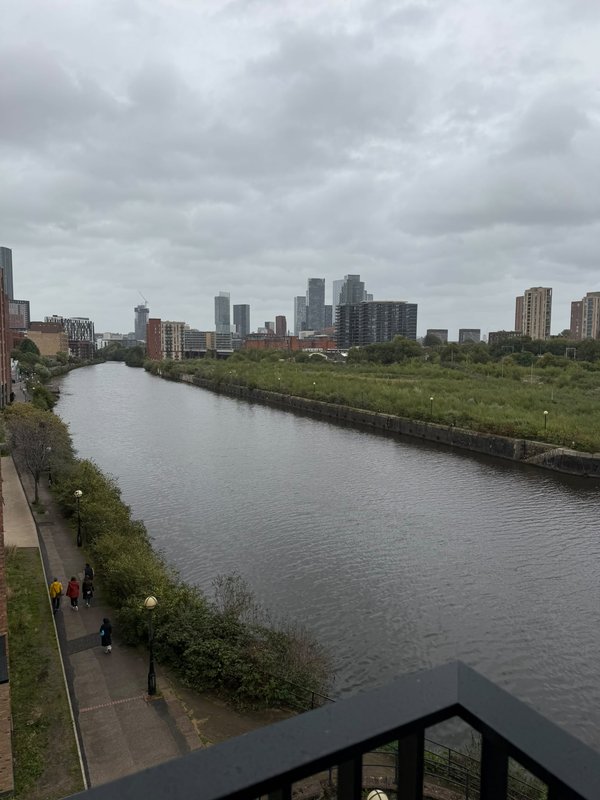 View from balcony overlooking river with city skyline and cloudy sky