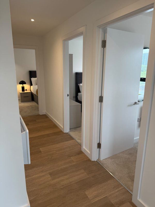 Hallway with wooden floor, white walls, doors to bedroom and bathroom