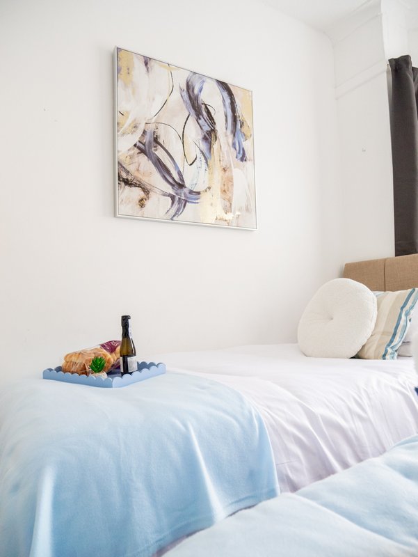 Bedroom with double bed, blue bedding, wall art, and welcome tray with wine bottle