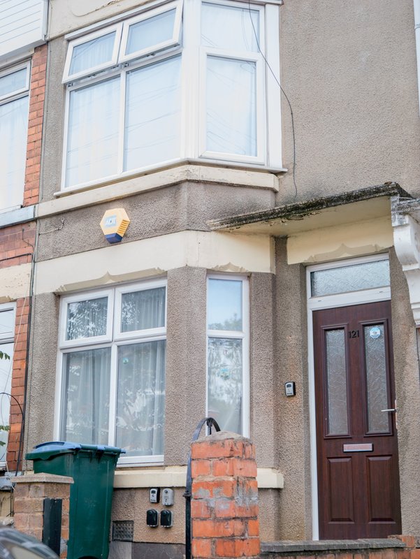 Brick and render terraced house exterior with bay windows, red door, and front entrance