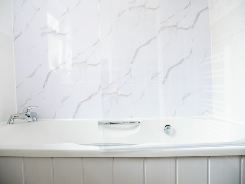 Modern bathroom with white marble tile wall and built-in bathtub with faucet