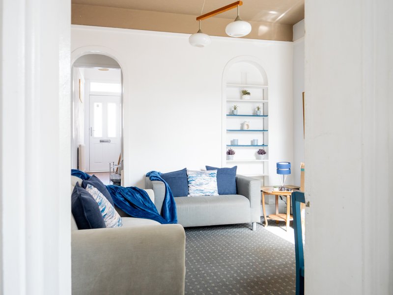 Bright living room with cream sofa, blue cushions, arched mirror and shelving unit