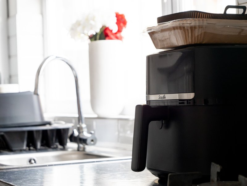 Modern kitchen counter with black coffee maker, sink, and white vase with flowers