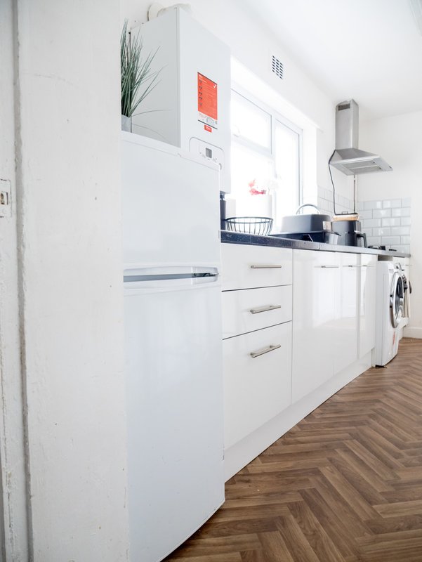 Modern white kitchen with appliances, countertop, and herringbone wood flooring