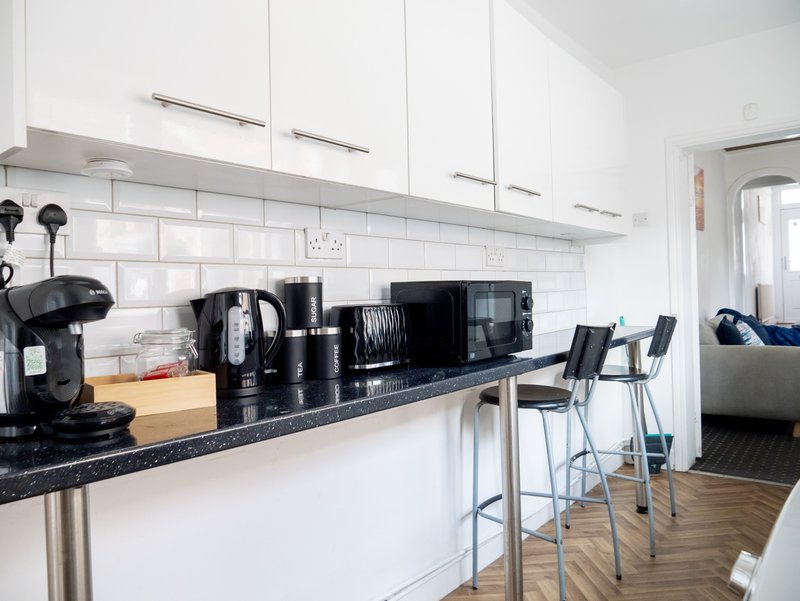 Modern kitchen with white cabinets, black countertop, appliances and bar seating