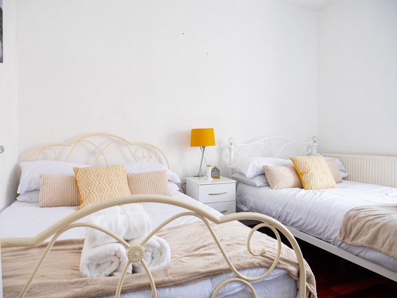 Twin bedroom with two metal-frame beds, patterned cushions, and bedside lamp