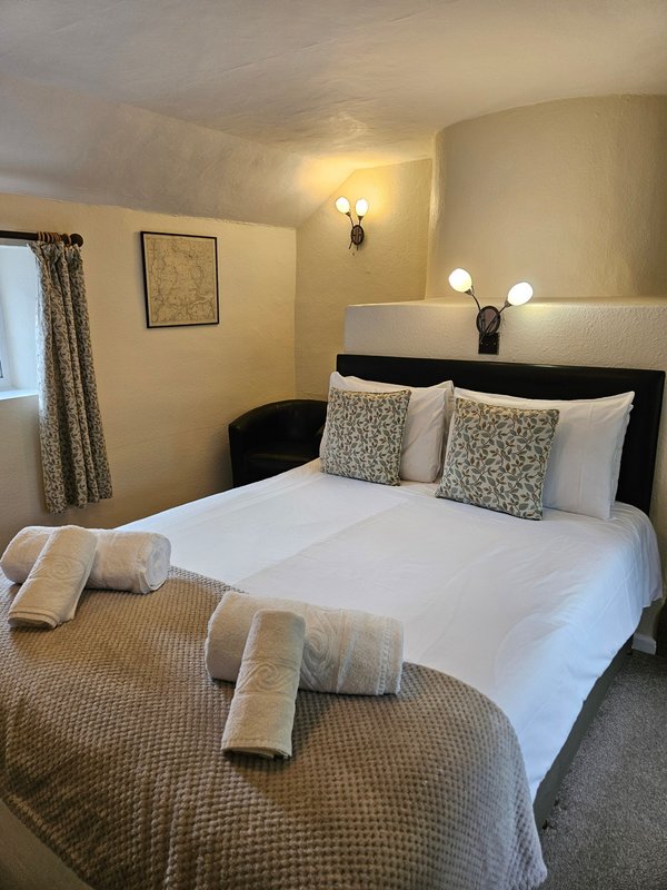 Cozy bedroom with double bed, rolled towels, patterned cushions and wall sconce lighting