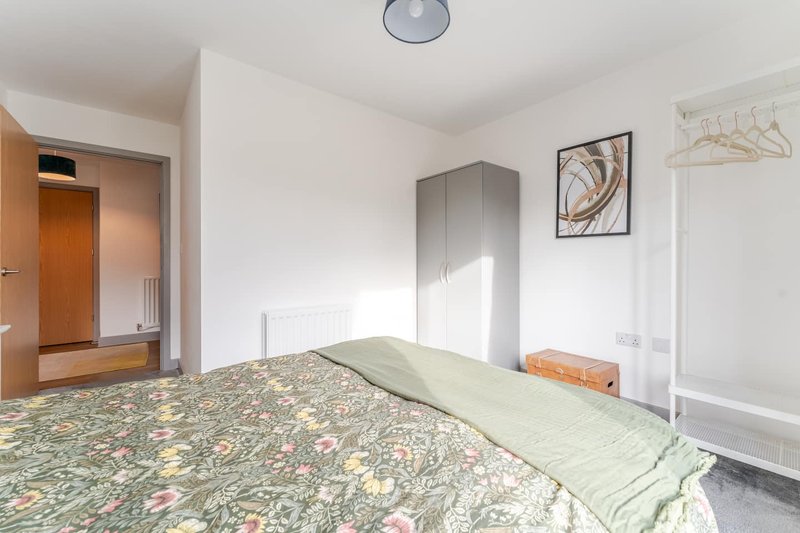 Bright bedroom with double bed, wardrobe, wall art, and wooden door to ensuite