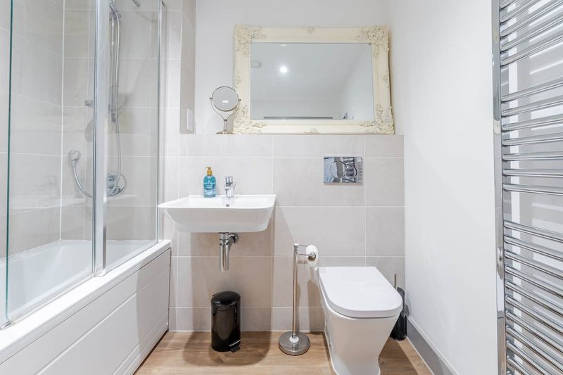 Clean modern bathroom with white sink, toilet, shower enclosure and heated towel rail