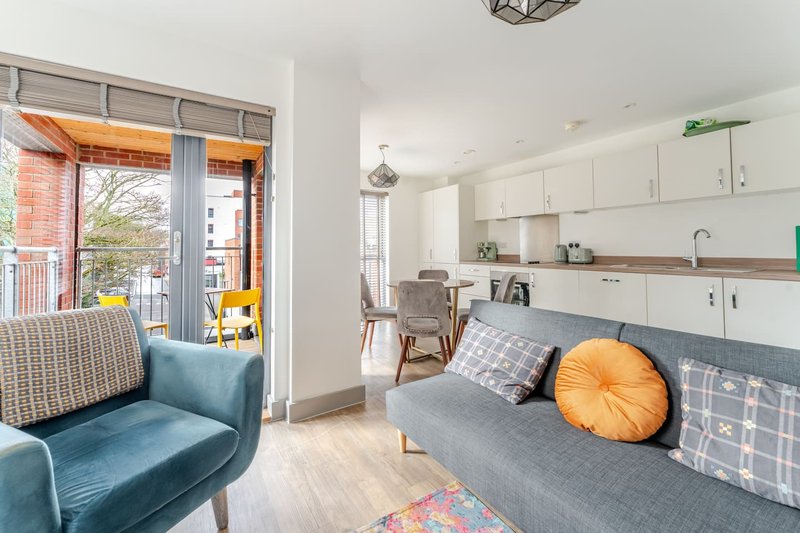 Modern open-plan living area with blue sofa, kitchen, and balcony access overlooking street