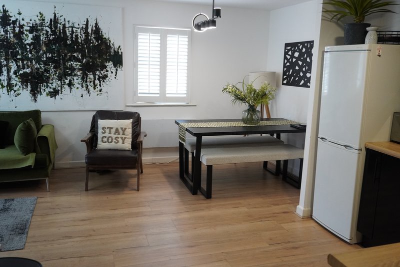 Open-plan living space with dining table, armchair, kitchen area and houseplants