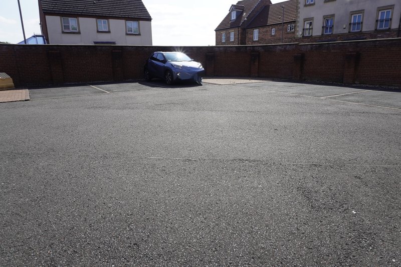 Driveway and parking area with parked car and surrounding residential buildings