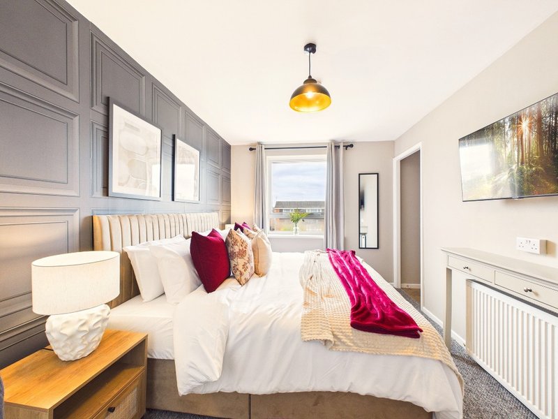 Modern bedroom with double bed, grey headboard, gold pendant light and countryside view