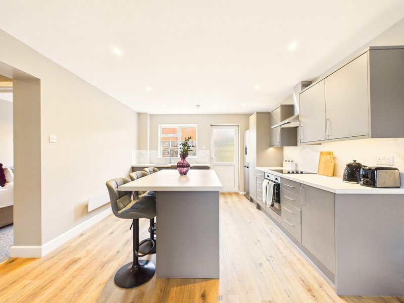 Modern kitchen with grey cabinetry, central island, wooden flooring and seating area