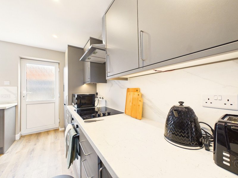 Modern kitchen with white cabinetry, gas hob, stainless steel extractor and countertop appliances