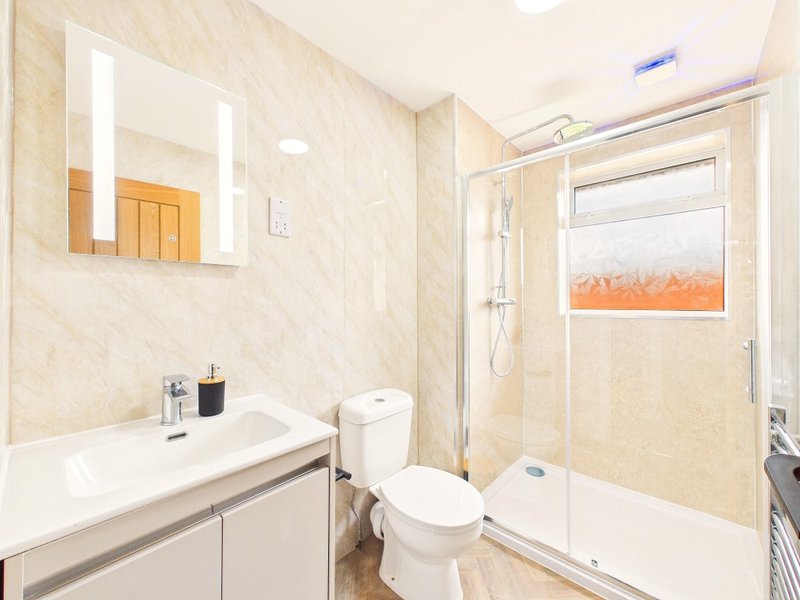Modern bathroom with white sink, toilet, glass shower enclosure and mirror cabinet