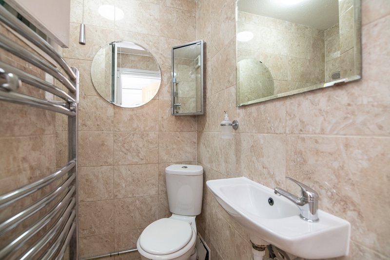 Modern bathroom with toilet, wall-mounted sink, heated towel rail and round mirror