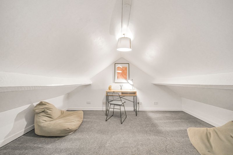 Bright attic room with sloped ceiling, bean bag chairs, desk, chair and pendant lighting