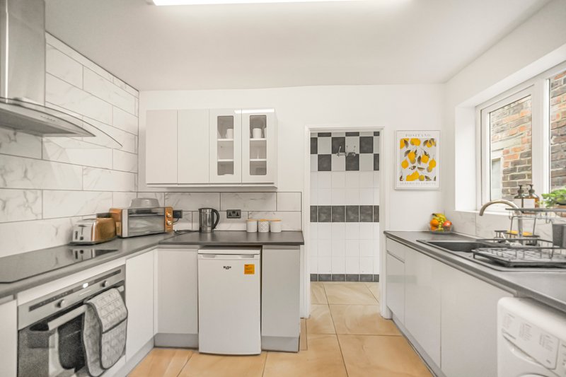 Modern white kitchen with subway tile splashback, stainless steel appliances and wooden floor