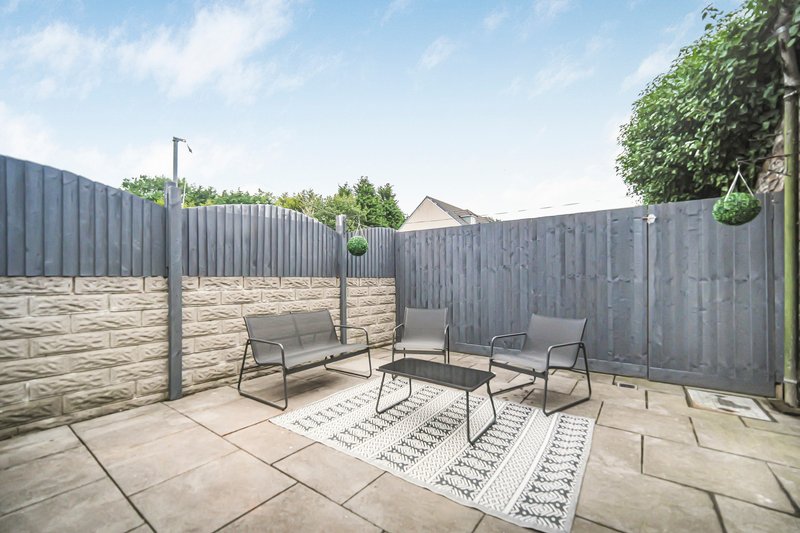 Enclosed outdoor patio with grey fencing, paved flooring, and modern seating furniture
