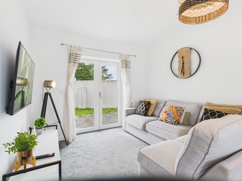 Bright living room with cream sofa, TV, patio doors, decorative cushions and wall art