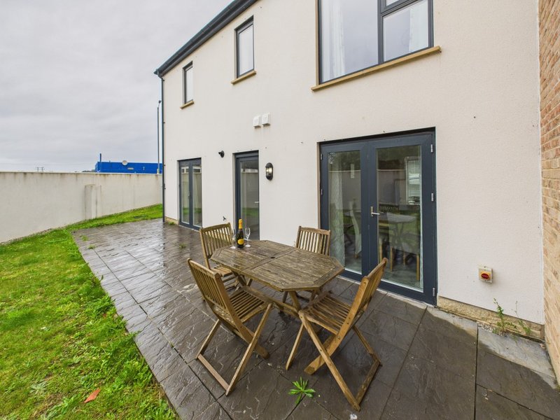 Modern house exterior with patio area, wooden garden furniture and manicured lawn