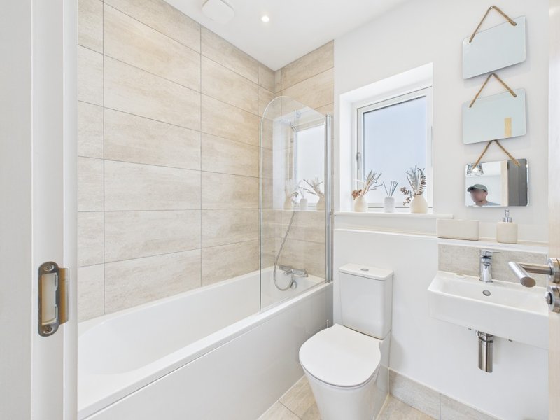 Modern bathroom with shower enclosure, toilet, sink and beige tile walls