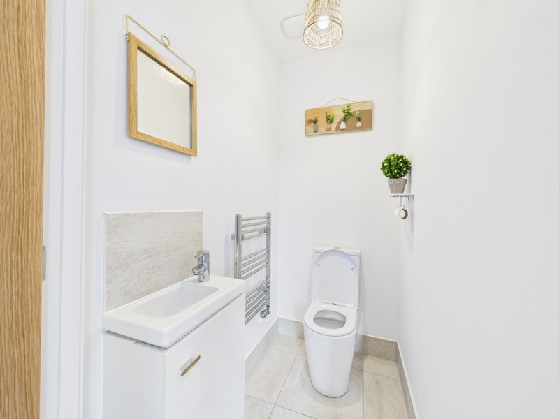Modern bathroom with white toilet, bathtub, heated towel rail and wooden door frame
