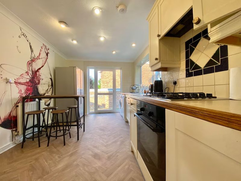 Kitchen with cream cabinets, wooden countertop, black cooker, and dining area with breakfast bar seating