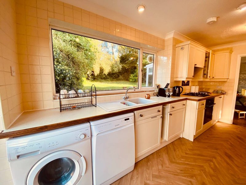 Kitchen with washing machine, dishwasher, sink and window overlooking garden