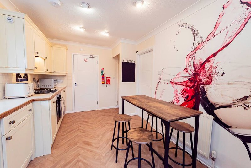 Modern kitchen and dining area with white cabinetry, wooden table, and abstract wall art