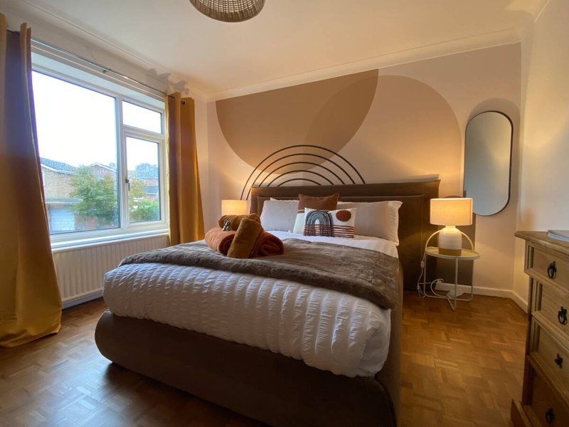 Modern bedroom with double bed, arched headboard, large window overlooking water, bedside lamps and furniture