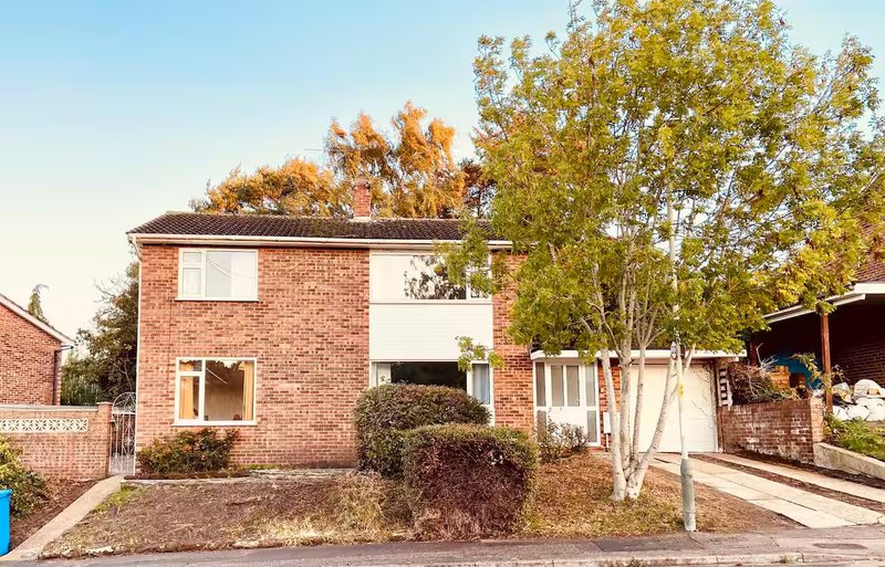 Brick semi-detached house with driveway, front garden and mature trees