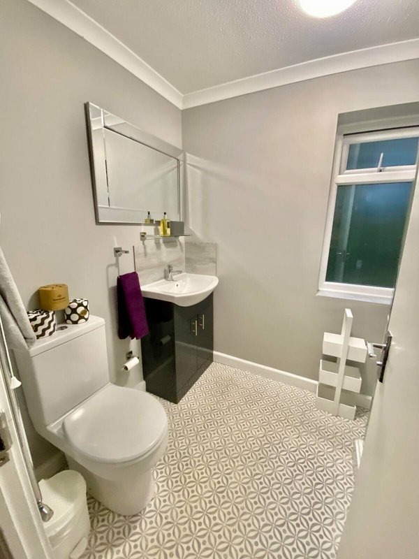 Modern bathroom with toilet, vanity sink, mirror, patterned floor tiles and window