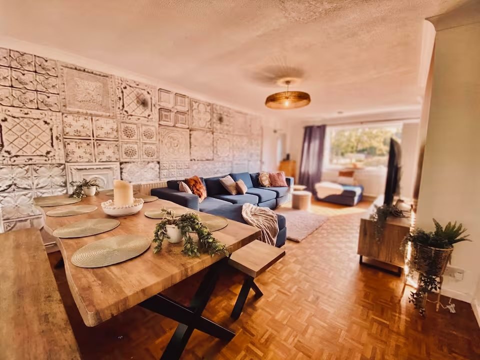 Open-plan living and dining area with wooden table, blue sofa, and decorative wall panels